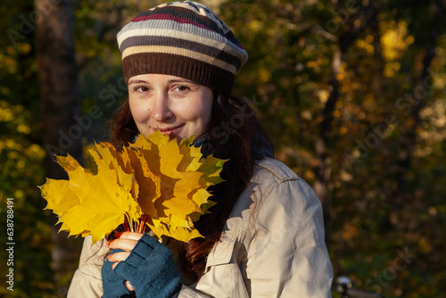 Woman with large yellow maple leaves in her hands..