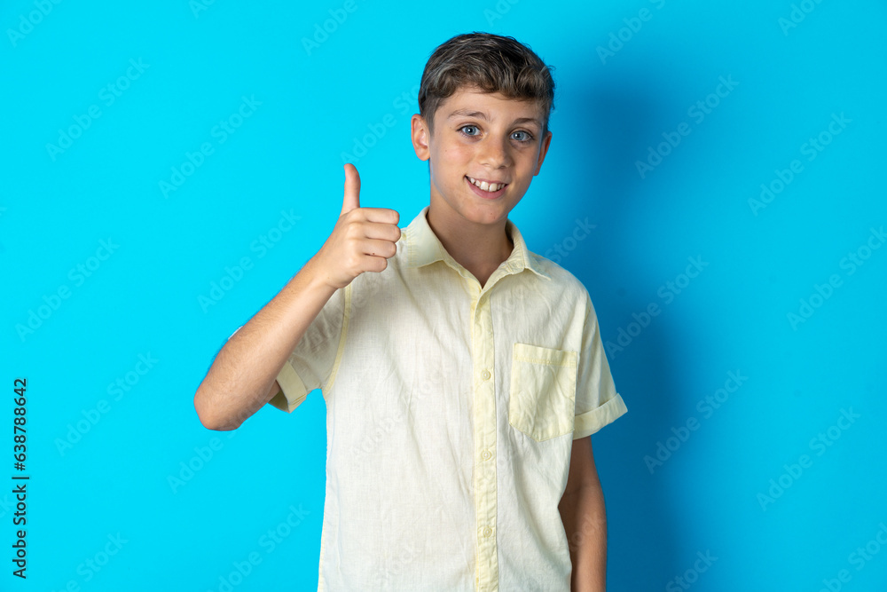 Beautiful kid boy wearing casual shirt doing happy thumbs up gesture with hand. Approving expression looking at the camera showing success. Beautiful kid boy wearing casual shirt doing happy thumbs up gesture with hand. Approving expression looking at the camera showing success.