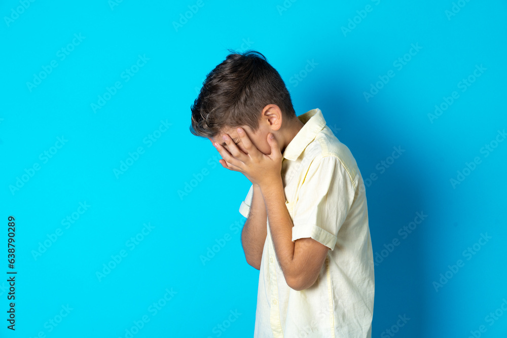 Sad Beautiful kid boy wearing casual shirt crying covering her face with her hands. Sad Beautiful kid boy wearing casual shirt crying covering her face with her hands.