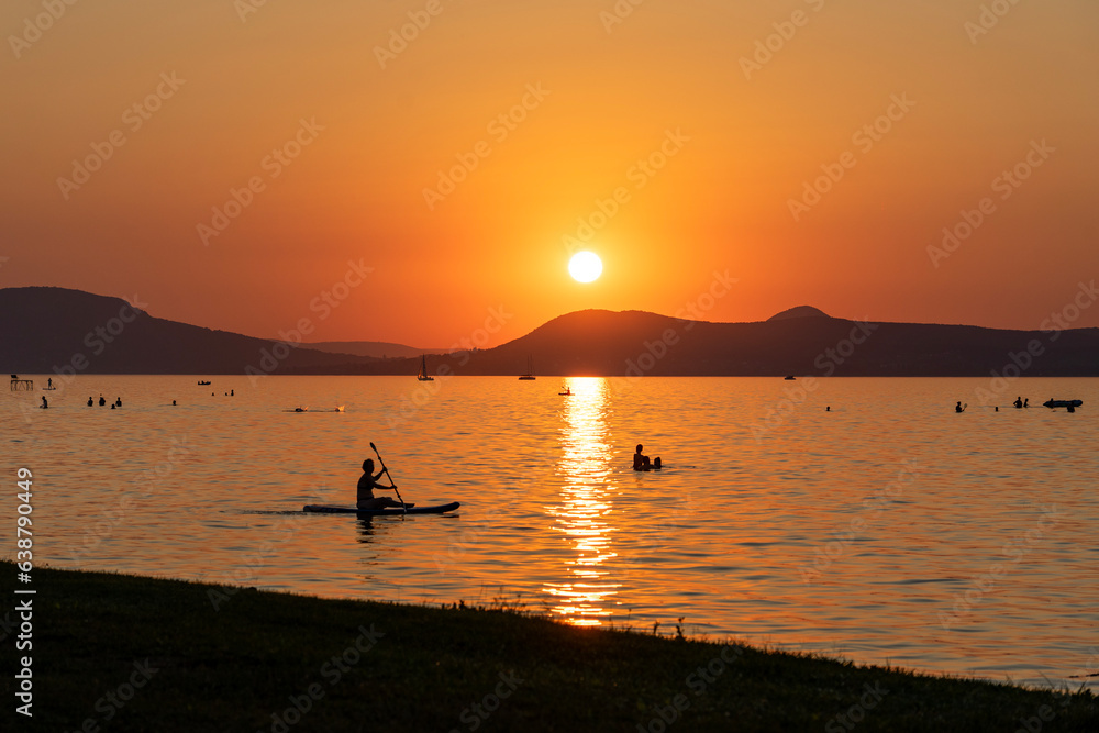 Lake Balaton at sunset with kayaking man silhouette and the north part mountains in the background