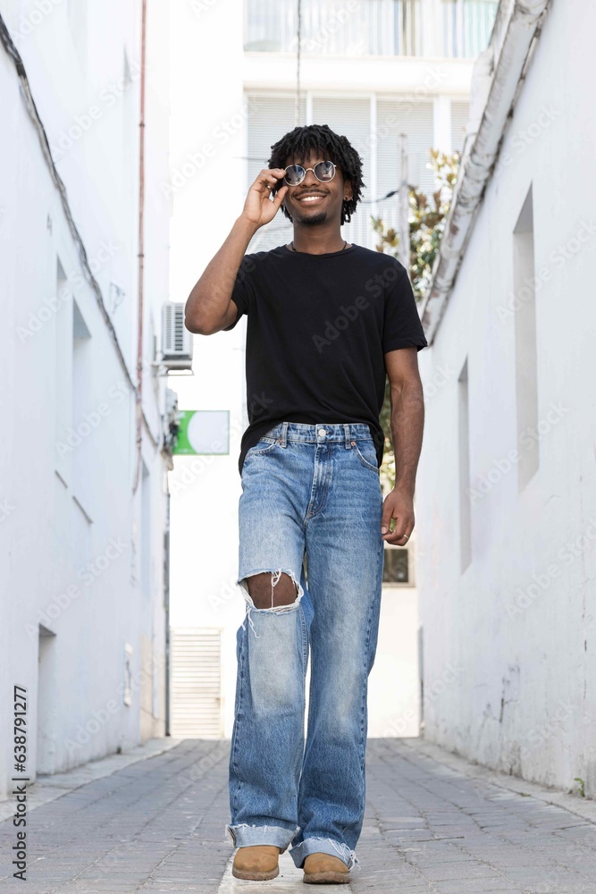 Young African American boy with curly hair walking at the street. Vertical photo