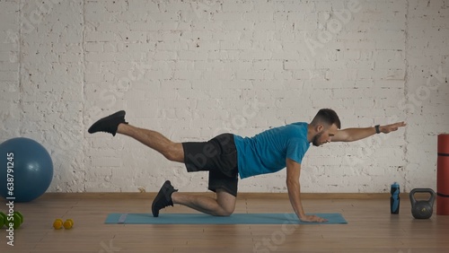 Man fitness instructor in sportswear doing back body strengthening exercise for online class at home. photo