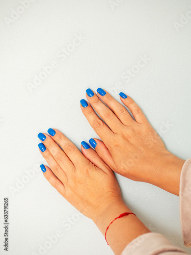 Female hand with high quality manicure  light color background. Blue color nail. Fashion and beauty concept. Professional skin and nail care.