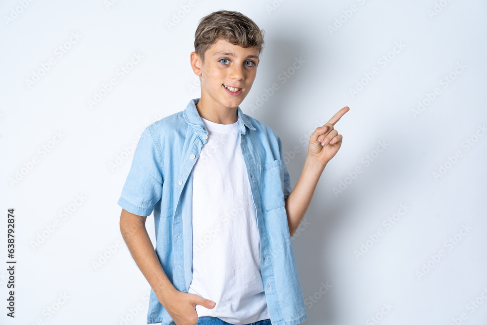 Beautiful kid boy wearing casual clothes looking at camera indicating finger empty space sales Beautiful kid boy wearing casual clothes looking at camera indicating finger empty space sales