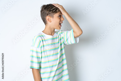Φωτογραφία Beautiful kid boy wearing striped casual t-shirt surprised with hand on head for mistake, remember error