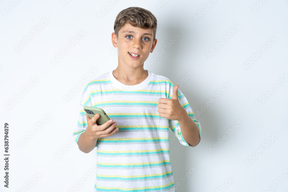 Portrait of Beautiful kid boy wearing striped casual t-shirt using and texting with smartphone happy with big smile doing ok sign, thumb up with fingers, excellent sign Portrait of Beautiful kid boy wearing striped casual t-shirt using and texting with smartphone happy with big smile doing ok sign, thumb up with fingers, excellent sign