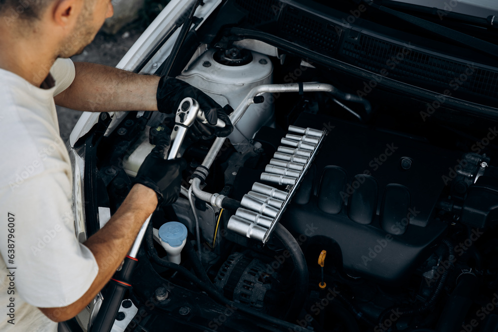The man holds socket head for a wrench for tightening and unrolling nuts and bolts. A set of adapters. Work in a car repair shop, service, garage. The man holds socket head for a wrench for tightening and unrolling nuts and bolts. A set of adapters. Work in a car repair shop, service, garage.
