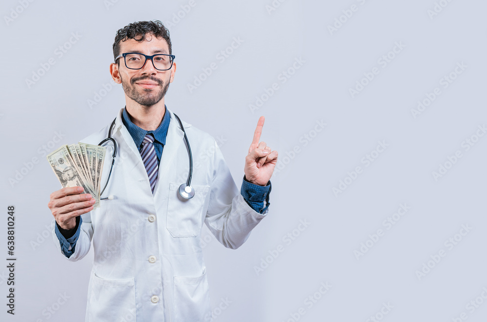 Handsome smiling doctor showing money and pointing side. Happy young doctor holding money and pointing to side. Latin doctor Handsome smiling doctor showing money and pointing side. Happy young doctor holding money and pointing to side. Latin doctor