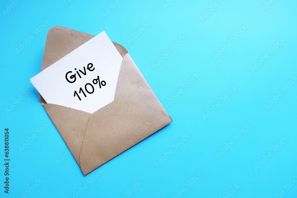 On blue copy space background, envelope with note written GIVE 110% - put absolute maximum amount of effort or energy possible - commitment to give it not less than 100 percent On blue copy space background, envelope with note written GIVE 110% - put absolute maximum amount of effort or energy possible - commitment to give it not less than 100 percent