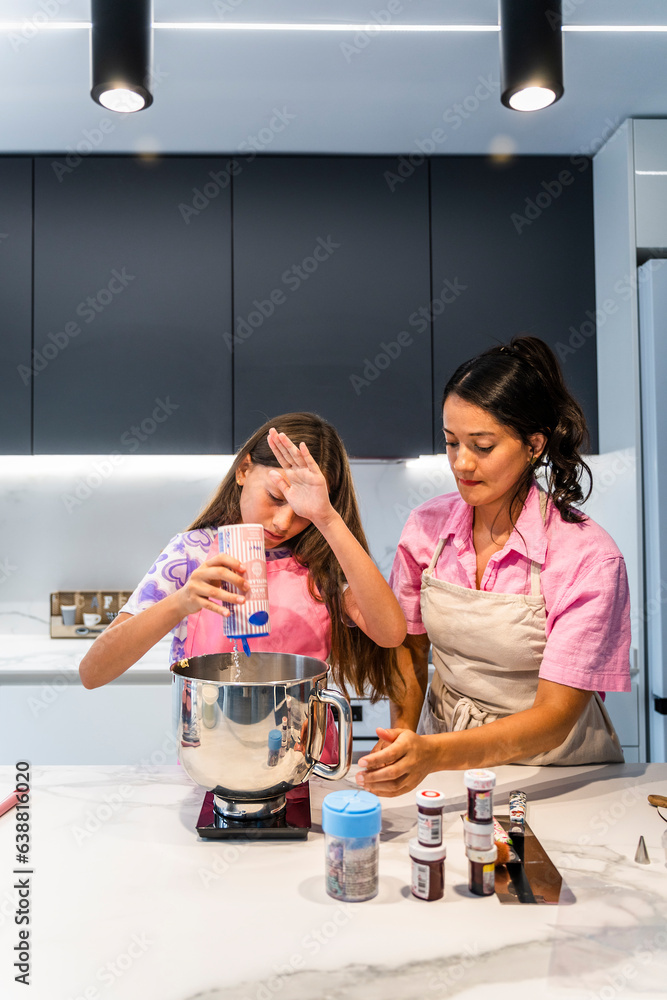 Cooking Family. Daughter and Mother adding sugar to the mix. Cooking Family. Daughter and Mother adding sugar to the mix.