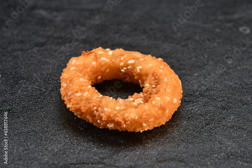 Crispy sesamed,fried single onion ring isolated black background