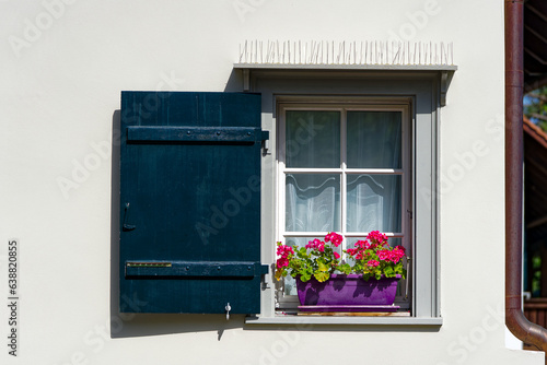 Idyllic view of window with wooden shutter and plant pot decoration with red flowers on a hot summer day at Swiss City of Z  rich. Photo taken August 24th  2023  Zurich  Switzerland.