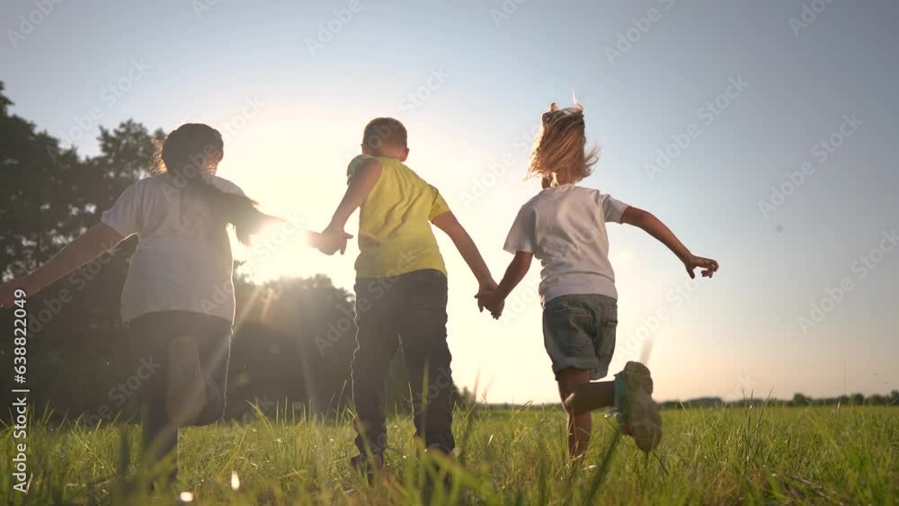 children running across the field holding hands. happy family childhood dream concept. several children run on the grass in summer lifestyle and have fun together. kids run on the grass at sunset children running across the field holding hands. happy family childhood dream concept. several children run on the grass in summer lifestyle and have fun together. kids run on the grass at sunset