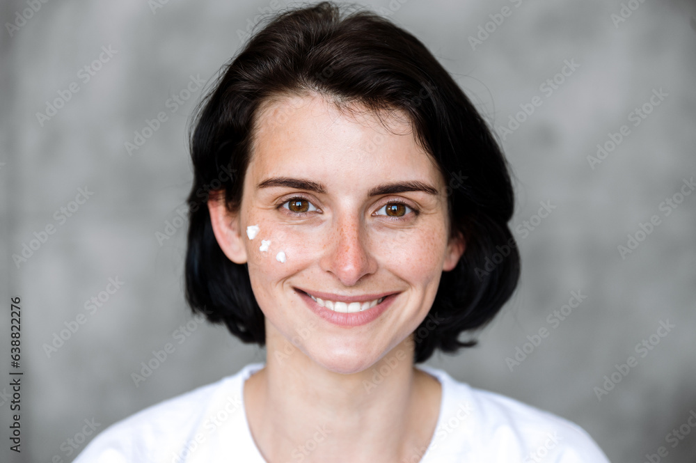 Young woman with healthy smooth skin and cream on cheeks Young woman with healthy smooth skin and cream on cheeks