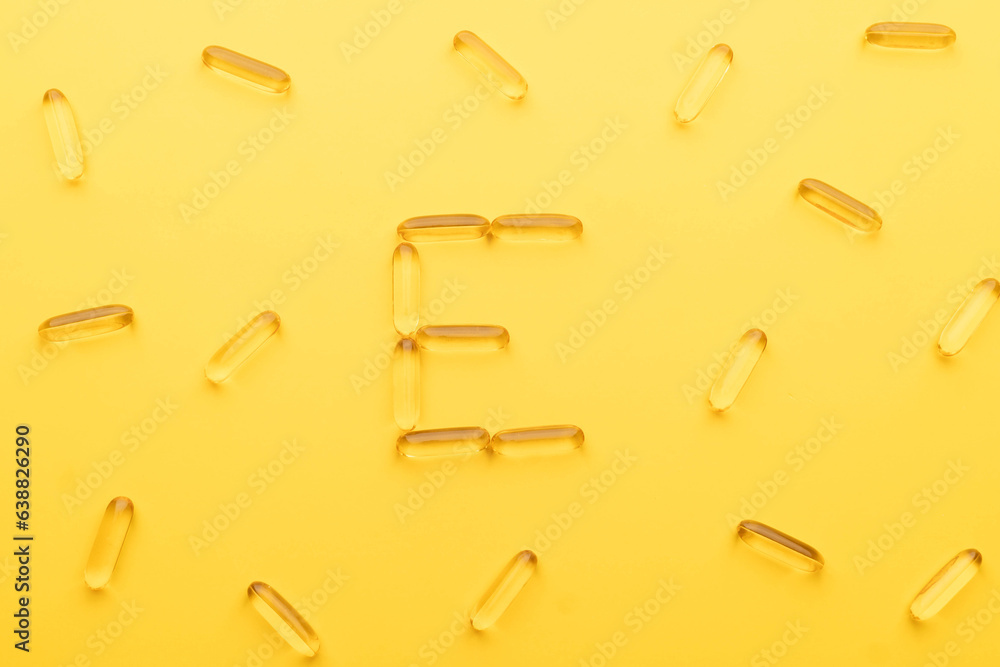 Vitamin E capsules with alphabet letter E on yellow background. Oil Softgel capsule uses for nutritional supplement, hair serum, skincare product and cosmetic ingredient. Vitamin E capsules with alphabet letter E on yellow background. Oil Softgel capsule uses for nutritional supplement, hair serum, skincare product and cosmetic ingredient.