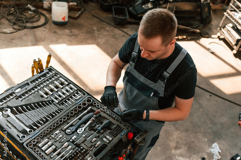 Tools for the repair in the box. Man is works in the automobile salon Tools for the repair in the box. Man is works in the automobile salon