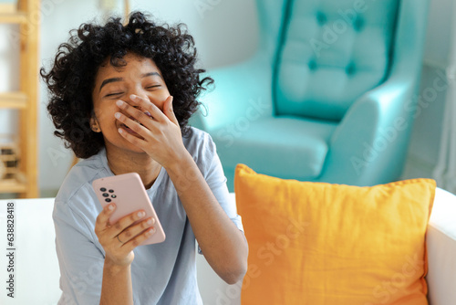 Foto Excited happy young black african american woman holding cell phone laughing feeling joy getting mobile message