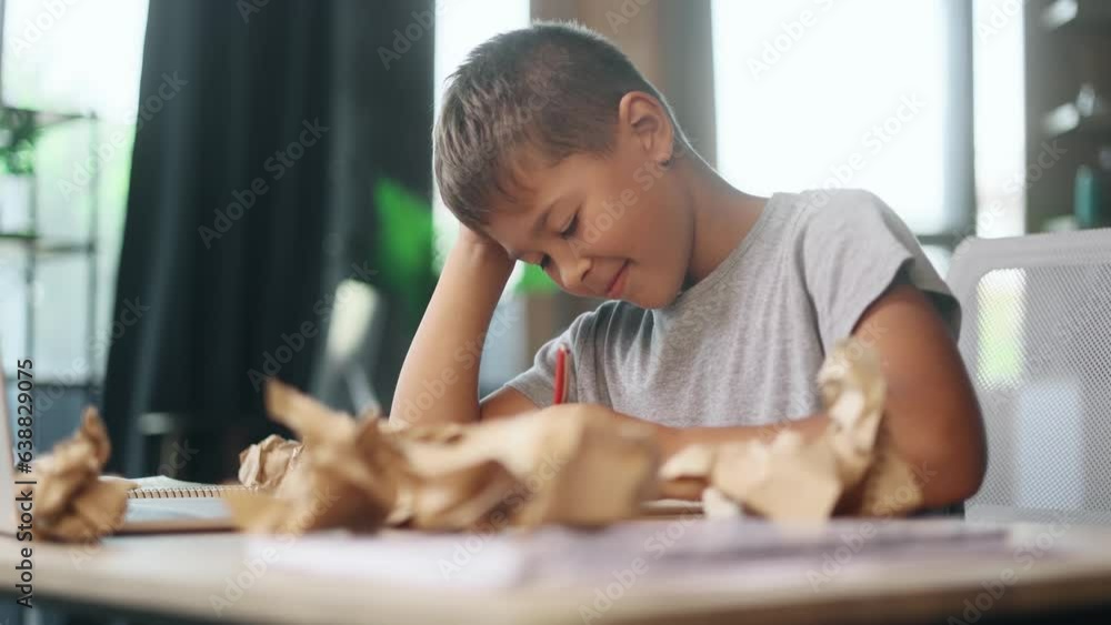 Portrait of exhausted school boy with failed crumped papers while writing in notebook at home Tired little kid child with creative block or lack of inspiration indoors Stress education concept Portrait of exhausted school boy with failed crumped papers while writing in notebook at home Tired little kid child with creative block or lack of inspiration indoors Stress education concept