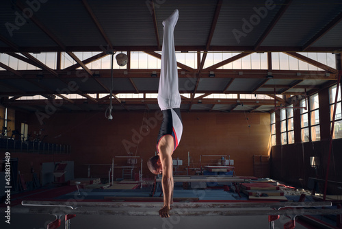 Young male gymnast doing exercises on the parallel apparatus.