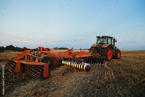 A tractor with a large disc harrow for tillage. Farmer work concept.