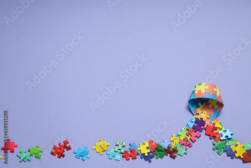 Ribbon with multi-colored puzzle pieces on a light background, place for text. World autism day concept
