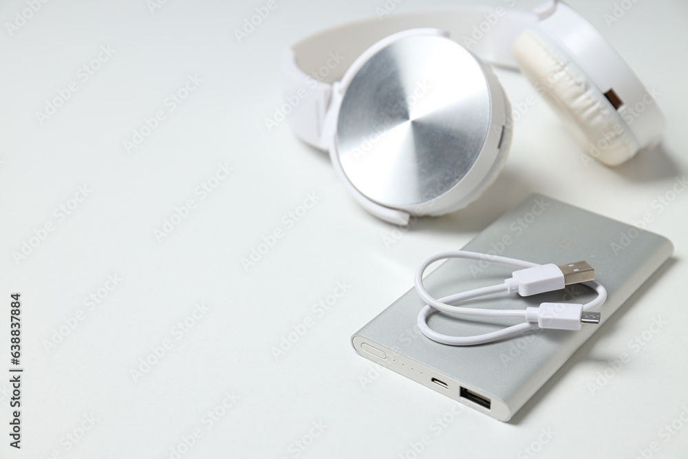 Powerbank, headphones and cord on white background, space for text Powerbank, headphones and cord on white background, space for text