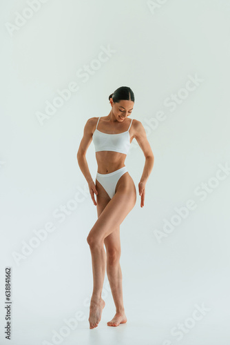 Against white background. Young woman with slim body type is in fitness clothes in the studio © standret