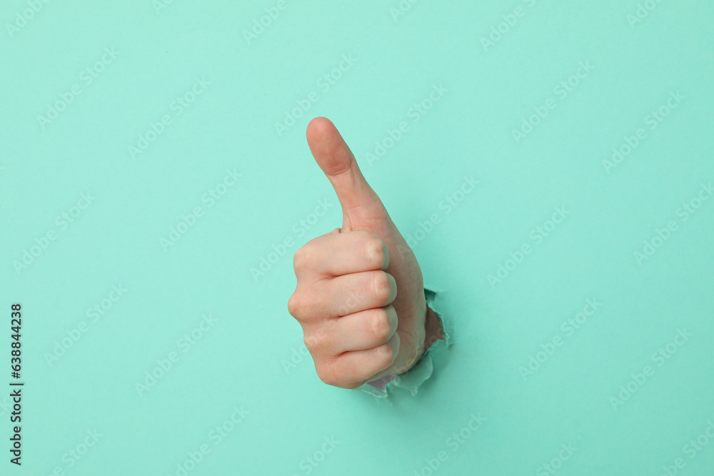 Female hand showing thumb up on turquoise background Female hand showing thumb up on turquoise background