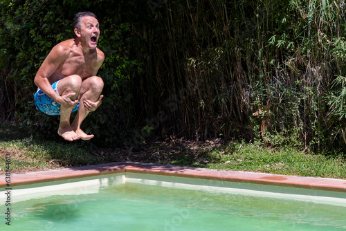 Foto Middle-aged white man dives into the pool cannonball style, with a comical expre