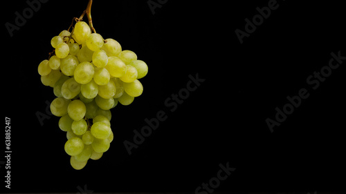 Branch of natural green grapes isolated on a black background