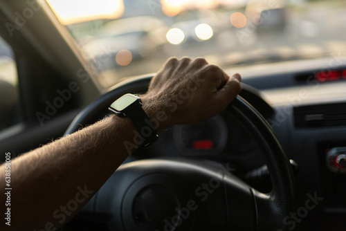 driving a car, the driver's hands on the steering wheel on a sunny day with a smart watch.