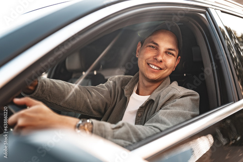 Young smiling man sitting in a car with open window © fotofabrika