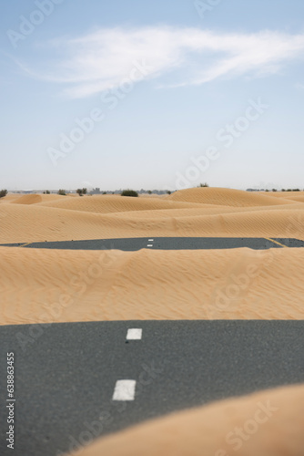 Obraz na płótnie (Selective focus) Stunning view of a deserted road covered by sand dunes. Empty road that run through the Dubai desert. Dubai, United Arab Emirates, (UEA) w salonie