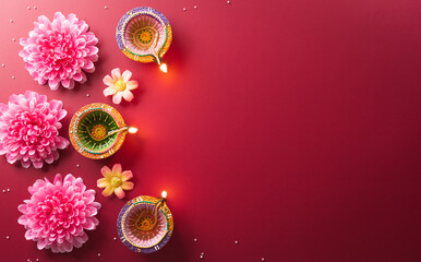 Happy Diwali - Clay Diya lamps lit during Diwali, Hindu festival of lights celebration. Colorful traditional oil lamp diya on red background