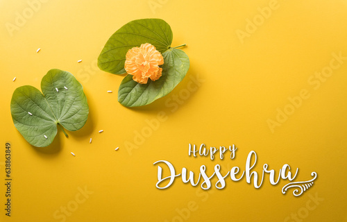 Happy Dussehra. Yellow flowers, green leaf, rice and the text on yellow paper background. Dussehra Indian Festival concept. photo