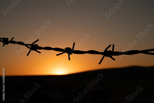 Sunset on the hill behind the barbed wire