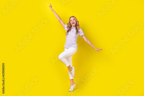 Full size photo of adorable girlish girl wear violet polo arms folded hold hands like wings flying isolated on yellow color background