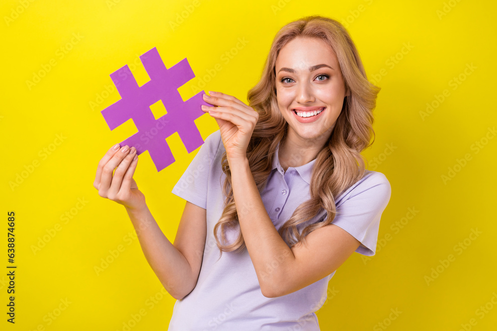 Photo of toothy beaming cute girl with curly hairstyle wear violet polo hands hold hashtag symbol isolated on yellow color background Photo of toothy beaming cute girl with curly hairstyle wear violet polo hands hold hashtag symbol isolated on yellow color background