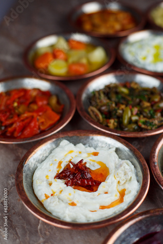 Spicy yogurt paste appetizer in a bronze bowl with other appetizers