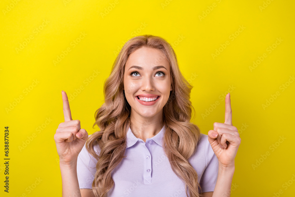 Photo of cute cheerful girl toothy smile look indicate fingers up empty space isolated on yellow color background Photo of cute cheerful girl toothy smile look indicate fingers up empty space isolated on yellow color background
