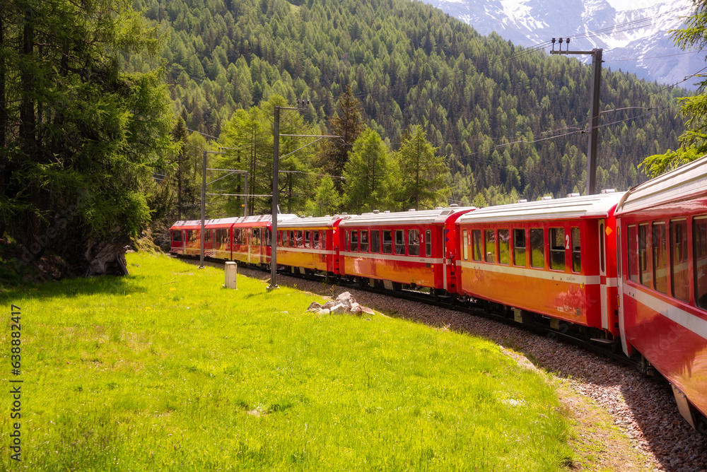 Naklejka premium Red train moving in beautiful green summer forest in Switzerland