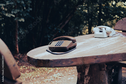 Old analog telephone on a wooden table in the forest