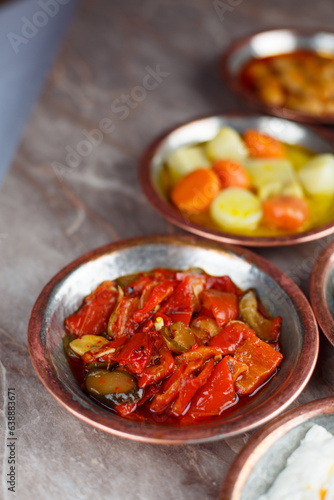 Red pepper with olive oil appetizer in a bronze bowl with other appetizers