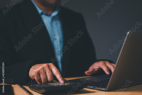 Businessman typed on a laptop computer, fingers flying over the keyboard as he calculated financial reports for the company. His eyes were focused on a screen, and face was serious as he worked