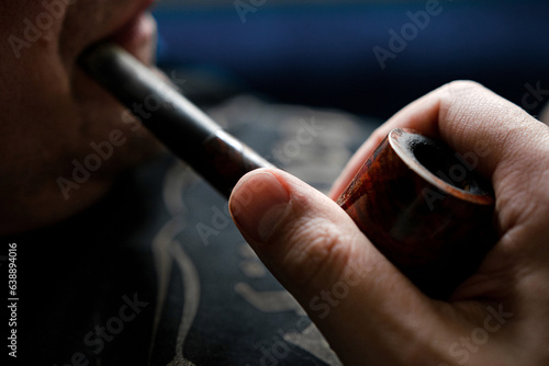 man's hand holding a smoking pipe