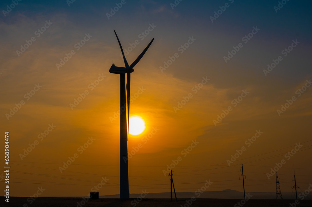 Obraz premium Windmill at sunset. Alternative energy source.