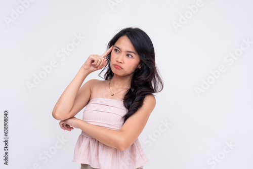 An undecided young asian woman considering her options. A puzzled lady in thought looking to the left. Isolated on a white background.