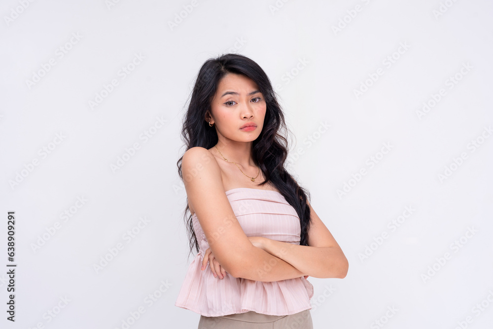 An annoyed young asian woman looking condescendingly and unimpressed at someone with arms crossed. Isolated on a white background. An annoyed young asian woman looking condescendingly and unimpressed at someone with arms crossed. Isolated on a white background.