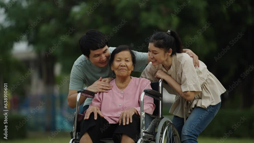 happy grandson and granddaughter talking with senior woman in wheelchair at the park happy grandson and granddaughter talking with senior woman in wheelchair at the park