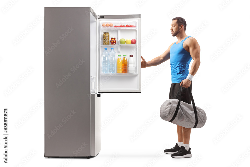 Male athlete holding a sports bag and opening a fridge Male athlete holding a sports bag and opening a fridge